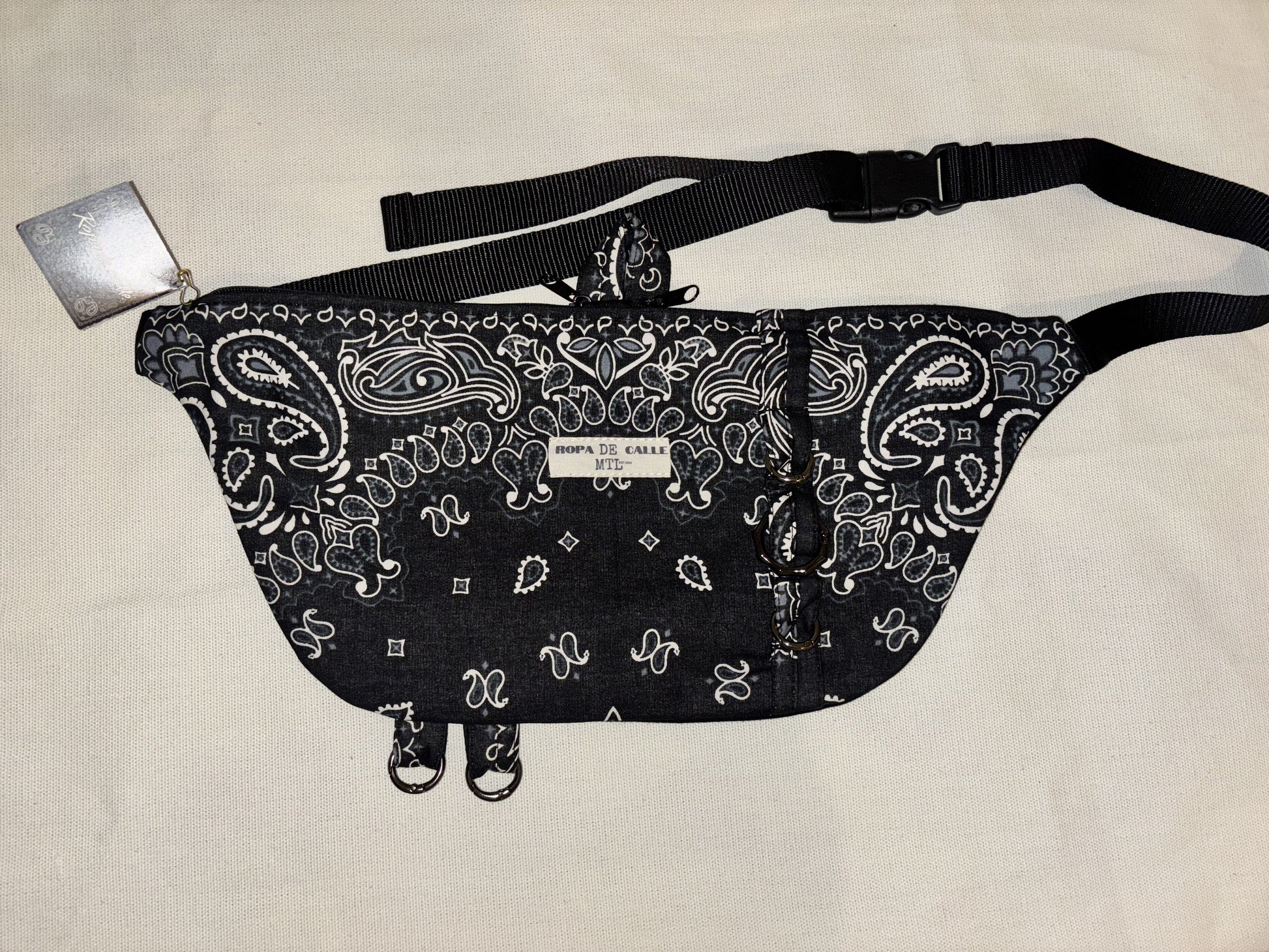 Black bandana-patterned bag with a strap on a beige background
